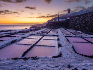 The Faro de Fuencaliente lighthouse and geometric salt pans at sunset, southern La Palma, with the volcanic coast behind.