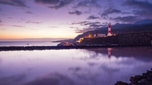 Faro de Fuencaliente lighthouse and salt pans mirrored in still water at violet twilight, southern La Palma.