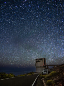Long-exposure star trails swirling over a large optical telescope housing at the Roque de los Muchachos observatory, La Palma.