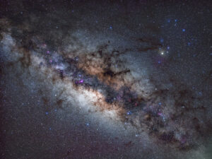 Tracked close-up of the Milky Way's galactic core showing dense star clouds, pink emission nebulae and dark dust lanes around the central bulge.