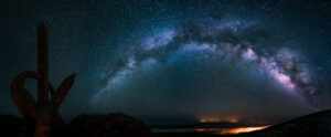 Panoramic nightscape: the Milky Way arching across the sky above a sculpted monument at the Roque de los Muchachos, La Palma.