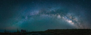 Panoramic nightscape of the Milky Way arching across the sky with a sculptural monument silhouetted in the foreground, La Palma.