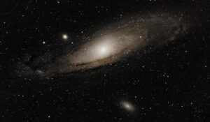 Deep-sky photograph of M31, the Andromeda Galaxy, with its companion satellites M32 and M110 visible against a star-filled field.