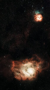 Deep-sky image of the Lagoon Nebula (M8) and the smaller Trifid Nebula (M20) in Sagittarius, glowing pink against dense star fields.