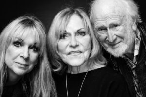 Black-and-white group portrait of three family members close together: two women and an elderly bearded man, all looking calmly at the camera.